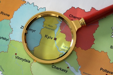 Golden magnifying glass above Kyiv region on map of Ukraine, closeup