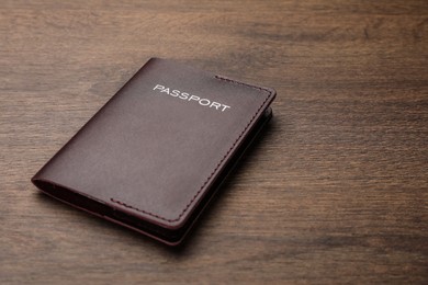 Passport in brown leather case on wooden table. Space for text