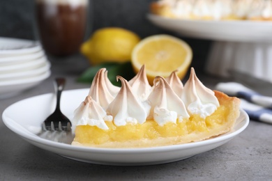 Photo of Piece of delicious lemon meringue pie served on grey table, closeup