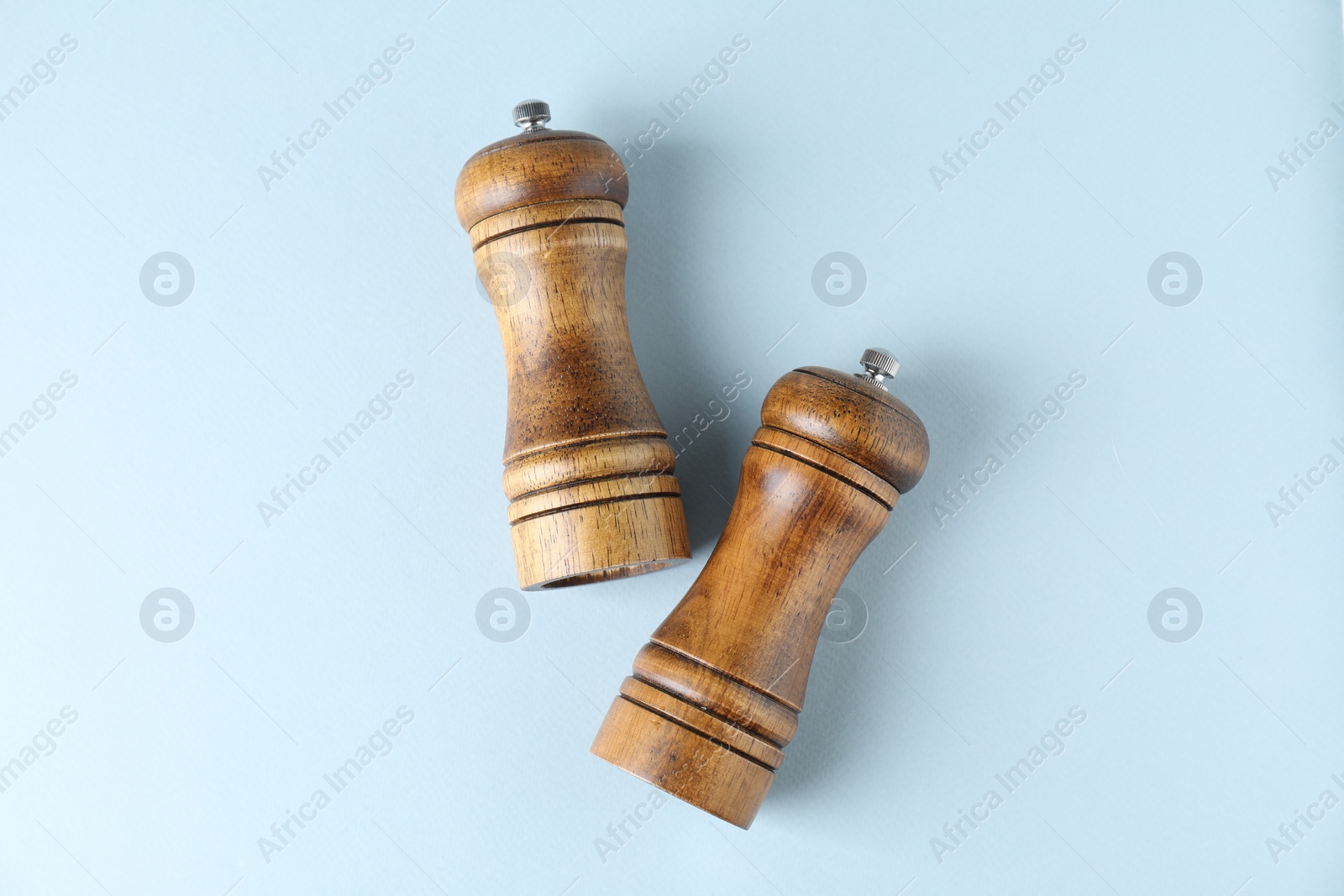 Photo of Wooden salt and pepper shakers on light background, top view