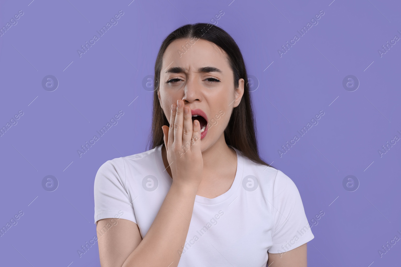 Photo of Tired young woman yawning on purple background. Insomnia problem