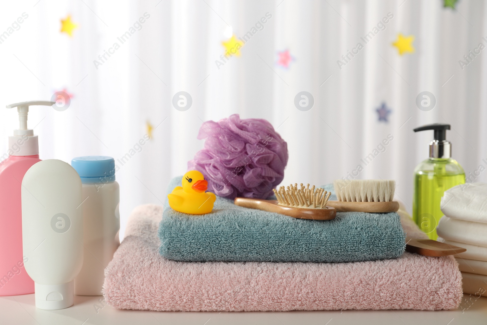 Photo of Towels, rubber duck and baby care products on white table indoors