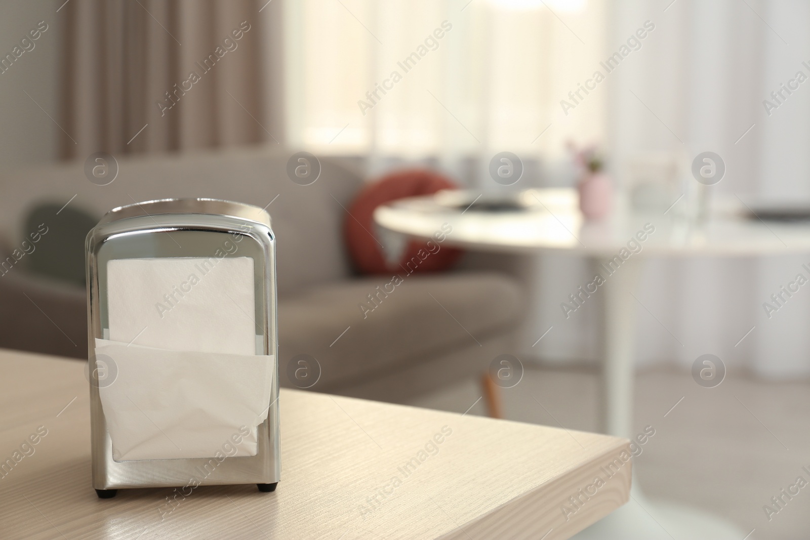 Photo of Napkin holder with paper serviettes on table in room. Space for text