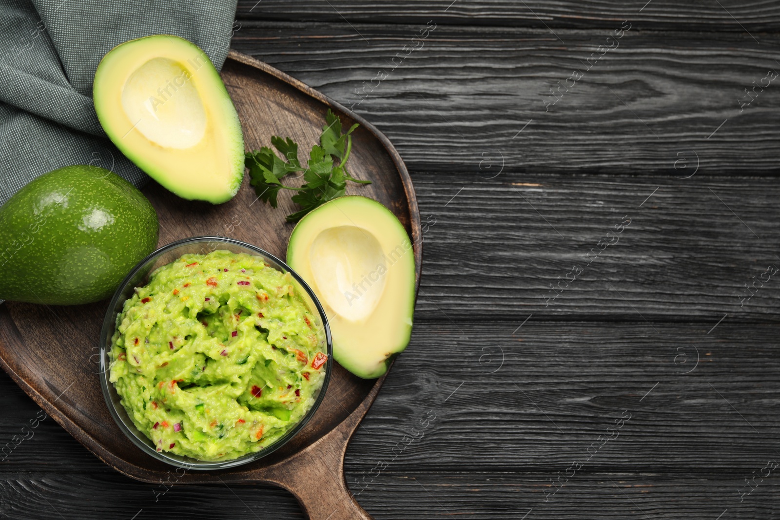 Photo of Delicious guacamole with parsley and fresh avocado on wooden table, flat lay. Space for text