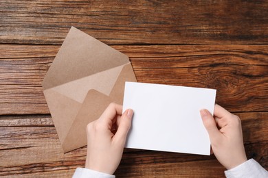 Woman with blank card at wooden table, top view. Space for text