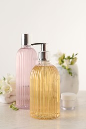 Photo of Liquid soap in stylish dispenser, bottle of shower gel and cream on white table