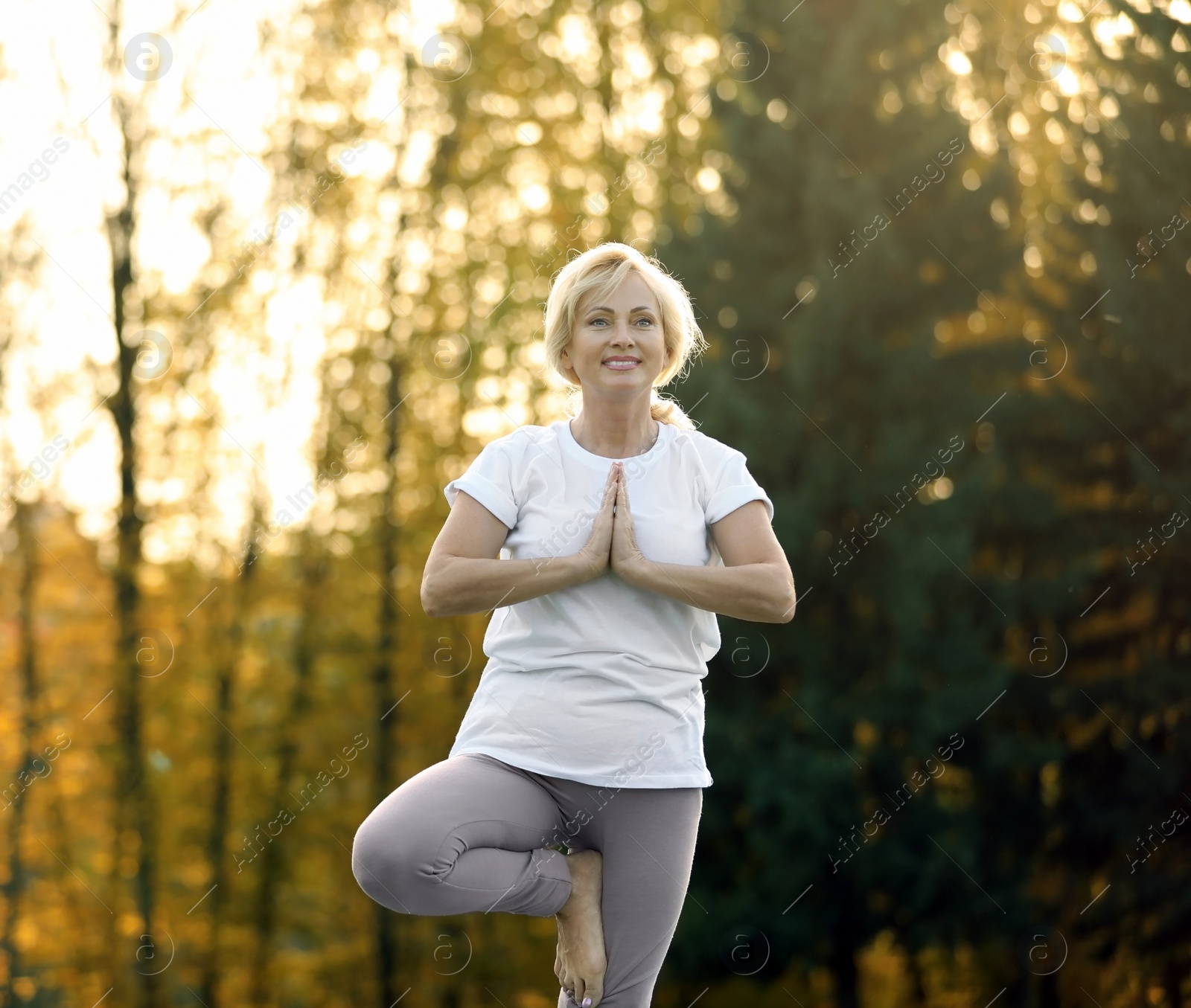 Image of Mature woman practicing yoga outdoors in morning