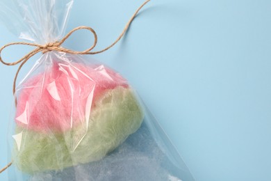 Photo of Packaged sweet cotton candy on light blue background, top view. Space for text