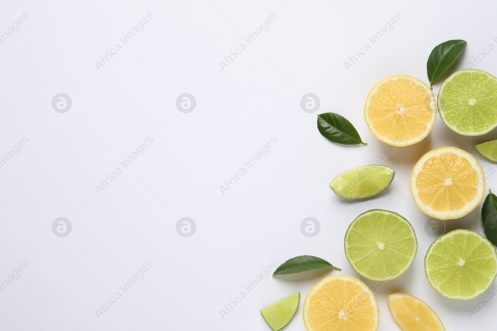 Photo of Fresh ripe lemons, limes and green leaves on white background, top view