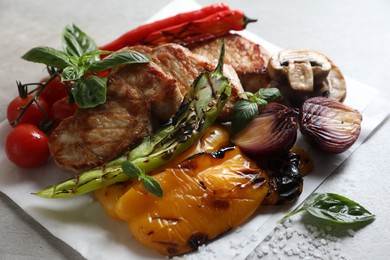 Photo of Tasty grilled meat and vegetables on light grey table, closeup