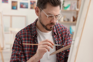 Photo of Man painting on canvas in studio. Creative hobby