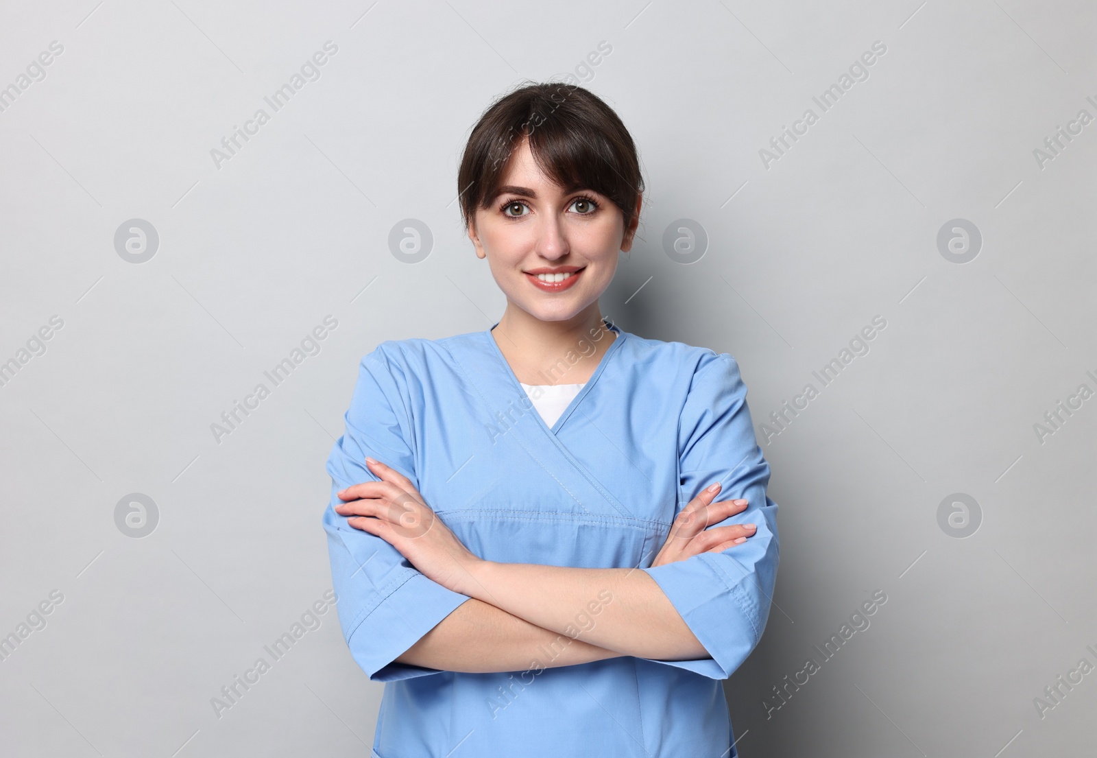 Photo of Portrait of smiling medical assistant with crossed arms on grey background