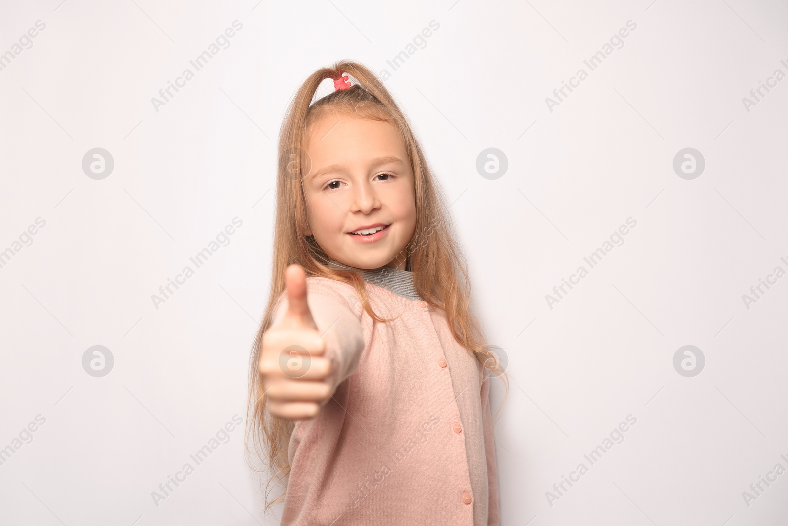 Photo of Happy little girl showing thumbs up on white background