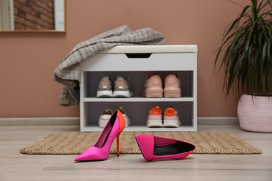 Photo of Shelving unit and stylish shoes on floor in hall