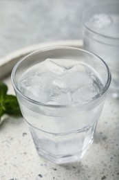 Photo of Glasses of soda water with ice and mint on marble tray, closeup