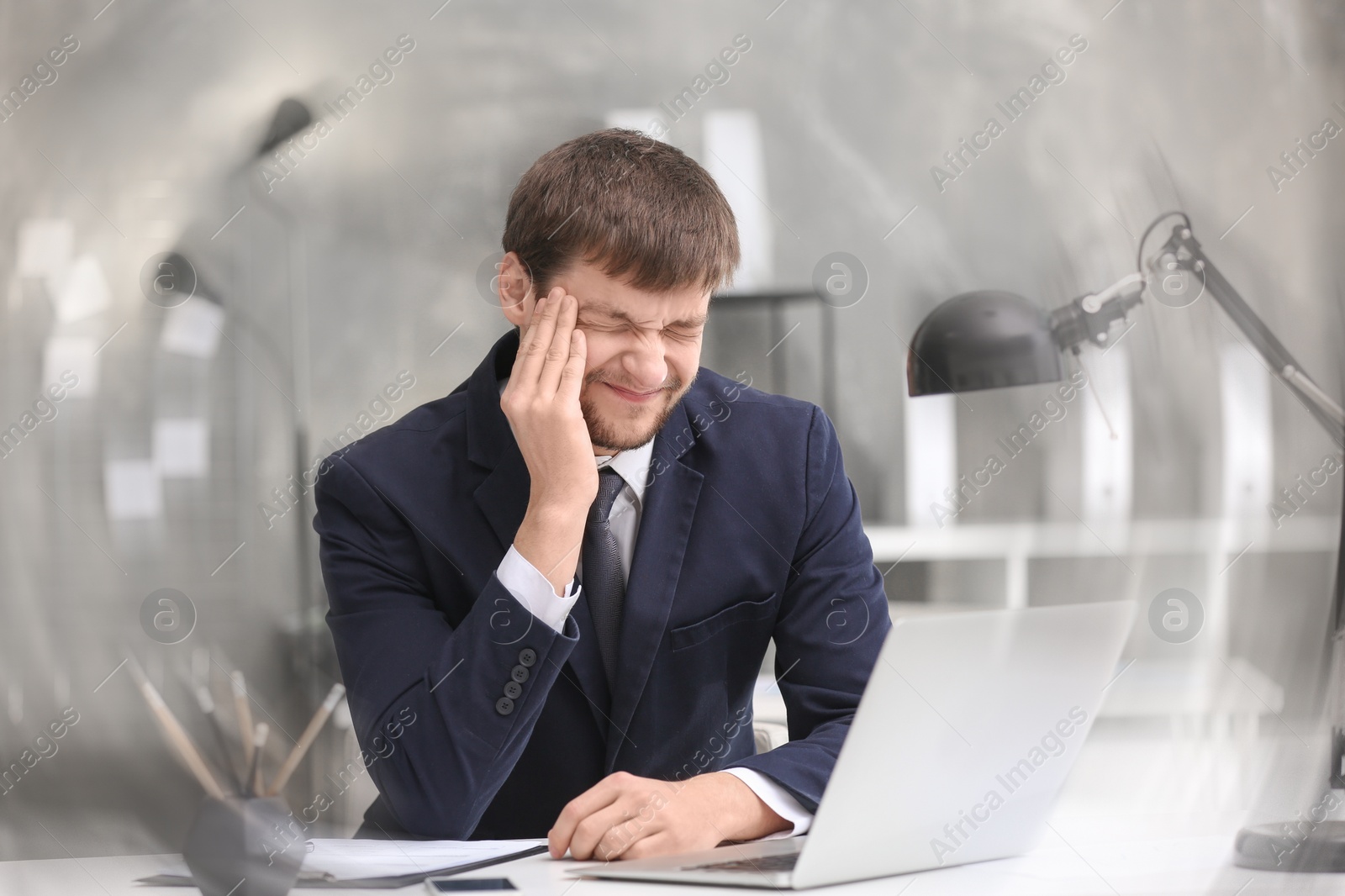 Photo of Young man suffering from headache in office