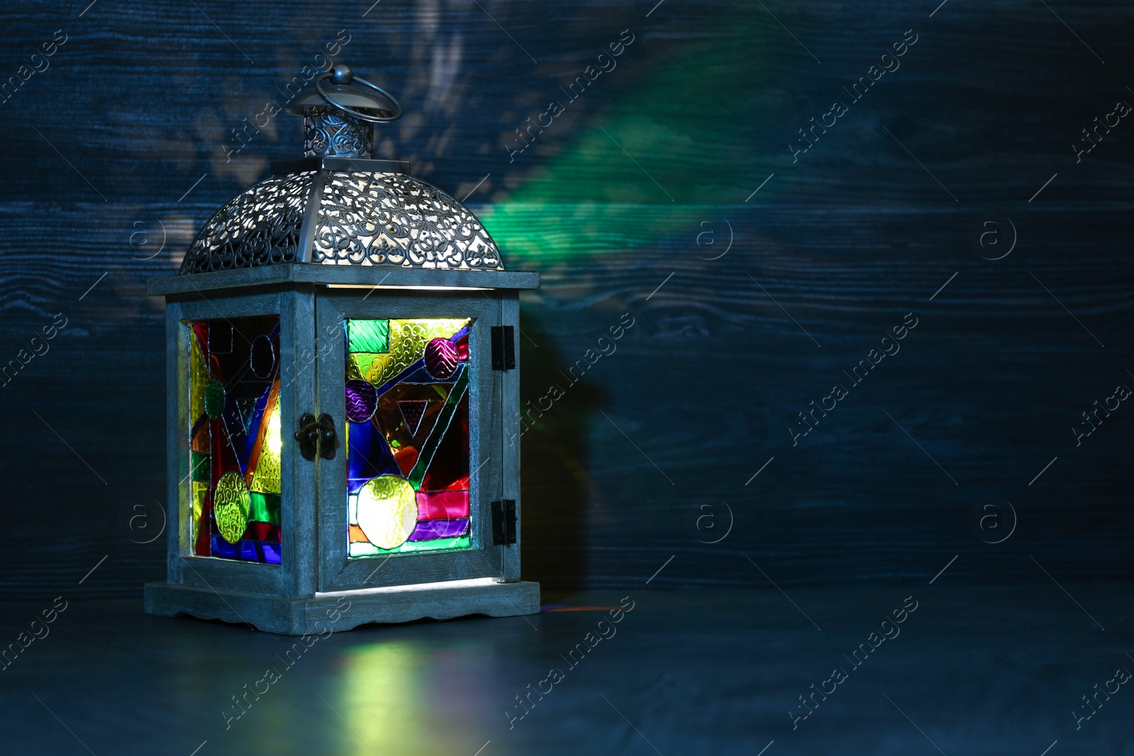 Photo of Decorative Arabic lantern on table against dark background. Space for text