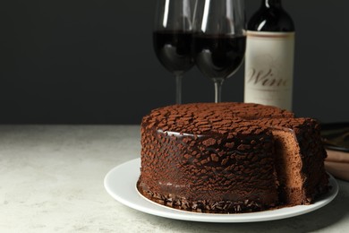 Photo of Delicious chocolate truffle cake and red wine on grey table, space for text