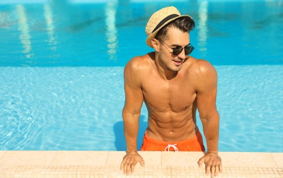 Young man in pool on sunny day, space for text