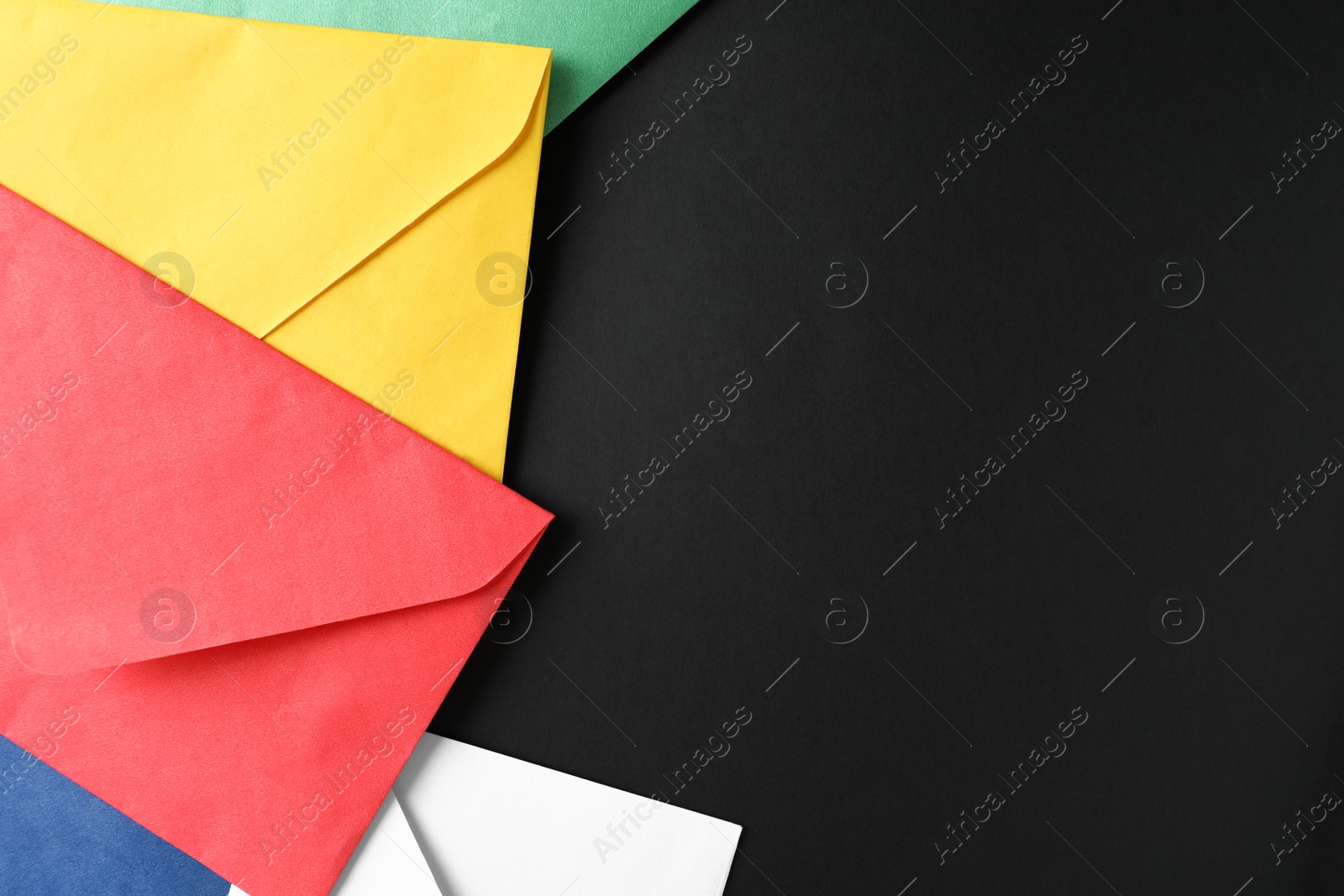 Photo of Colorful paper envelopes on black background, flat lay. Space for text