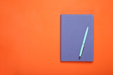 Photo of Closed blue notebook and pen on orange background, top view. Space for text