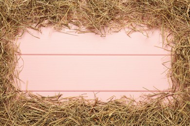 Photo of Frame of dried hay on pink wooden background, flat lay. Space for text