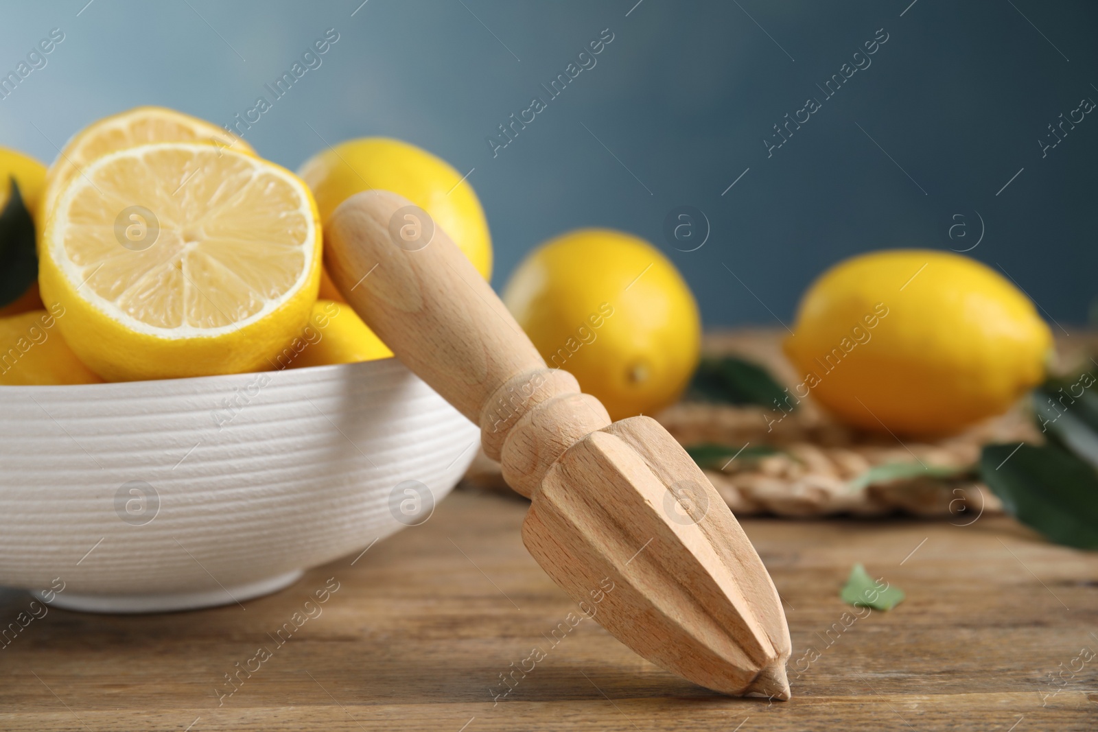 Photo of Squeezer with lemons on wooden table, closeup