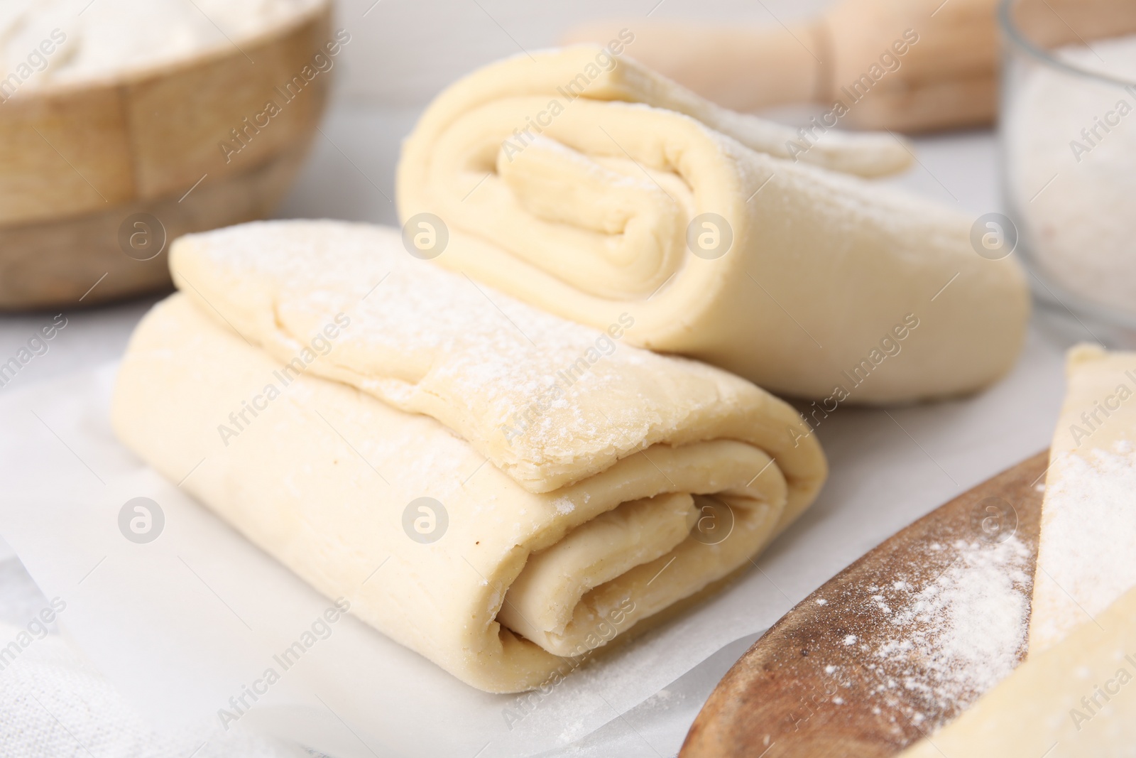 Photo of Raw puff pastry dough on white table, closeup