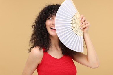 Photo of Happy woman holding hand fan on beige background