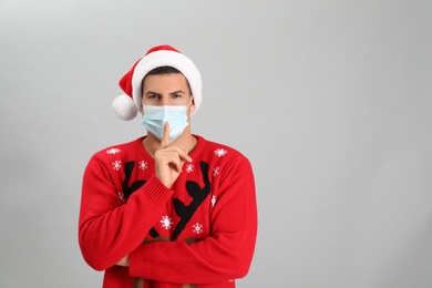 Photo of Man wearing Santa hat and medical mask on grey background, space for text