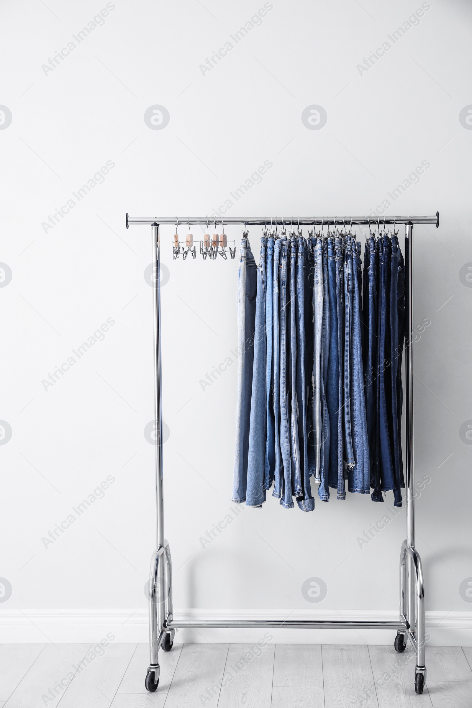 Photo of Rack with different jeans near white wall