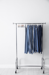 Photo of Rack with different jeans near white wall