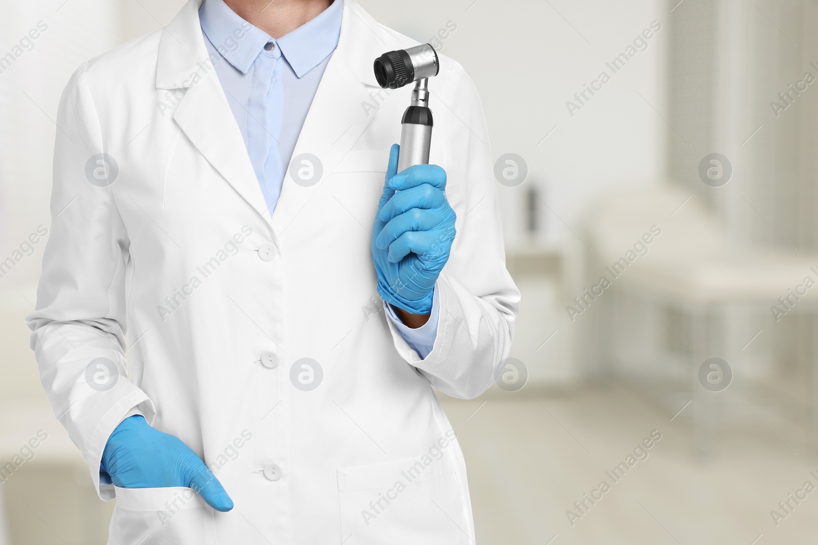Image of Professional dermatologist with dermatoscope on blurred background, closeup