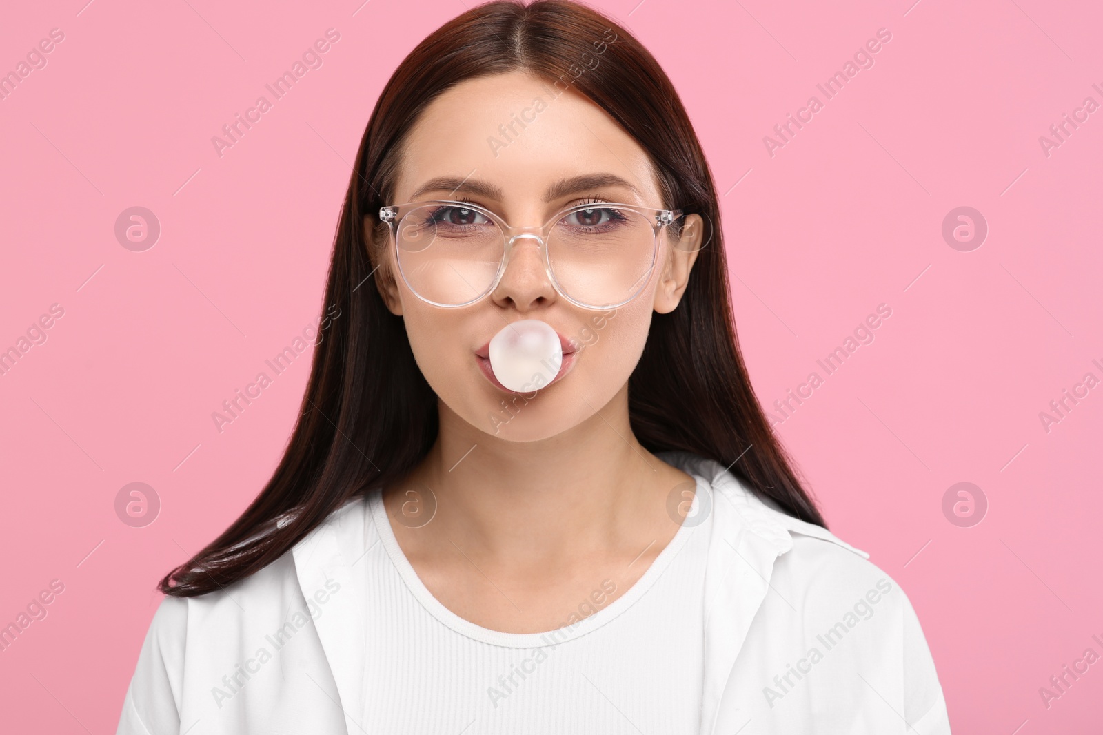 Photo of Beautiful woman blowing bubble gum on pink background