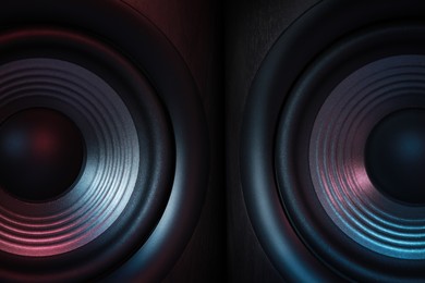 Photo of Modern sound speakers in neon light as background, closeup