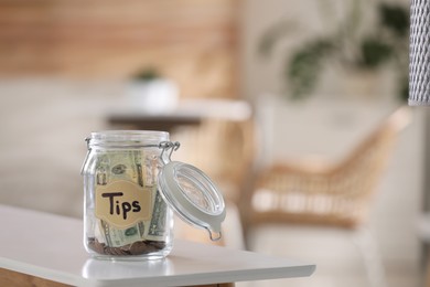 Photo of Glass jar with tips on table indoors. Space for text