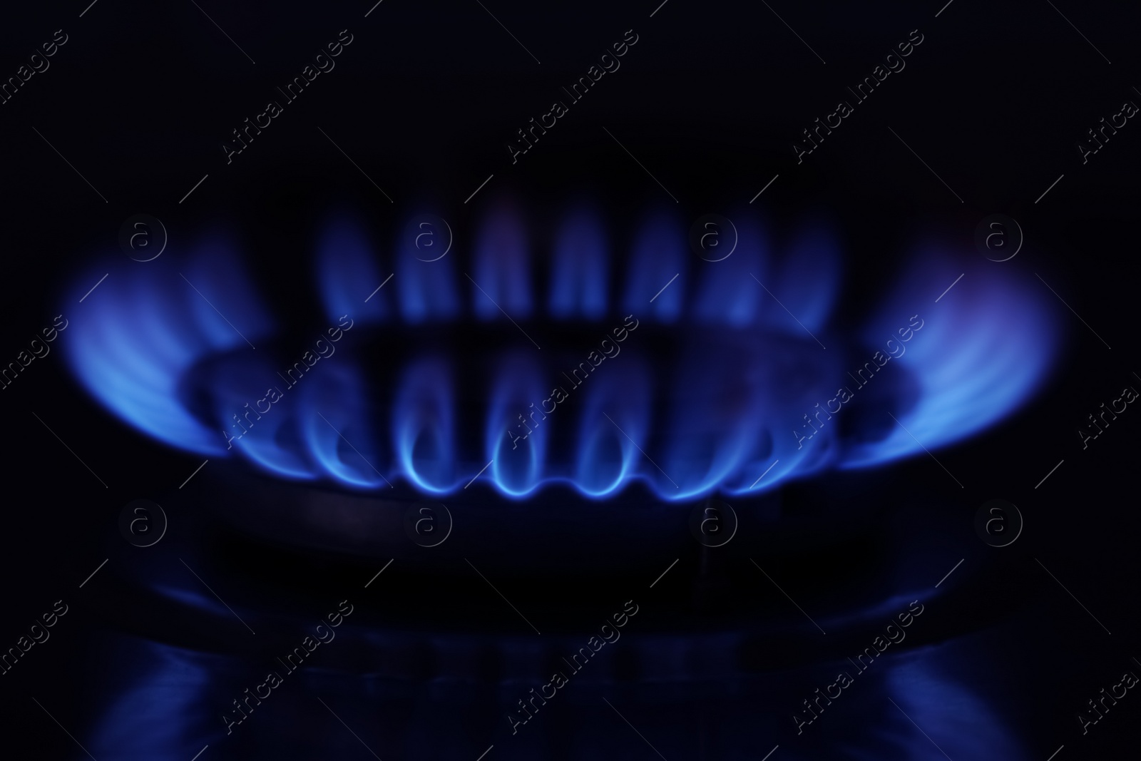 Photo of Gas burner with burning flame in darkness, closeup