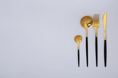 Stylish golden cutlery set on gray background, flat lay. Space for text