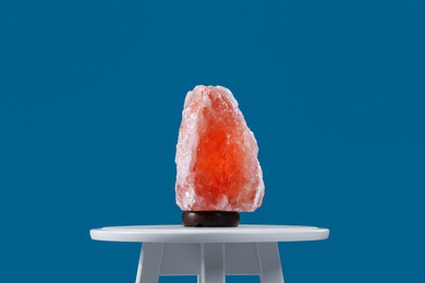 Himalayan salt lamp on white table against blue background