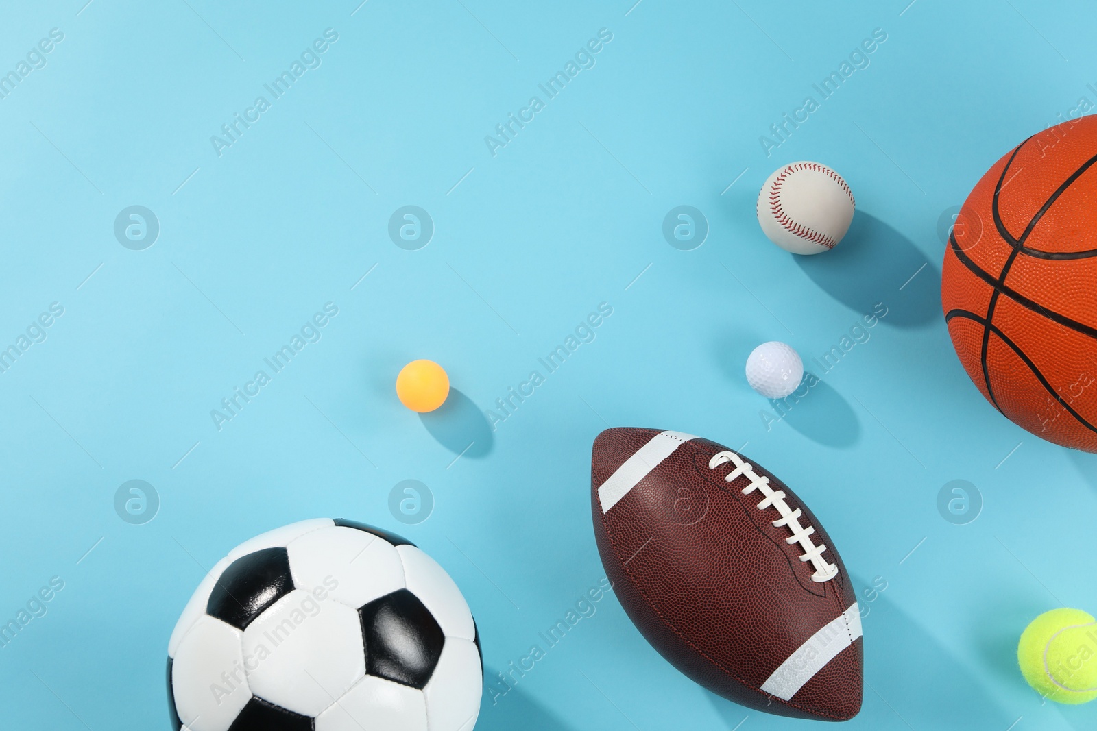 Photo of Many different sports balls on light blue background, flat lay. Space for text