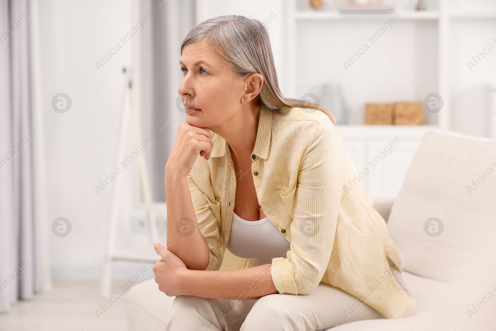 Photo of Menopause, mood changes. Sad woman on sofa at home, space for text