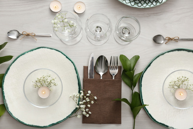 Elegant table setting with green plants on white wooden background, flat lay