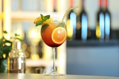 Photo of Fresh alcoholic cocktail with orange and mint on bar counter