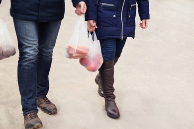 People carrying plastic bags with products outdoors, closeup