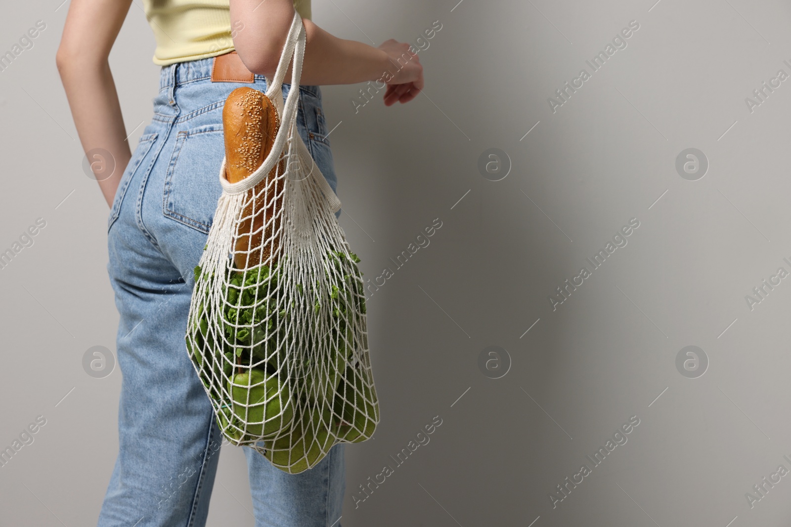 Photo of Woman with eco bag full of products on light background, closeup. Space for text