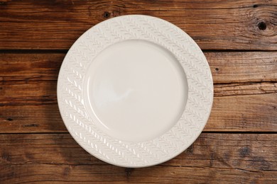 Photo of One ceramic plate on wooden table, top view