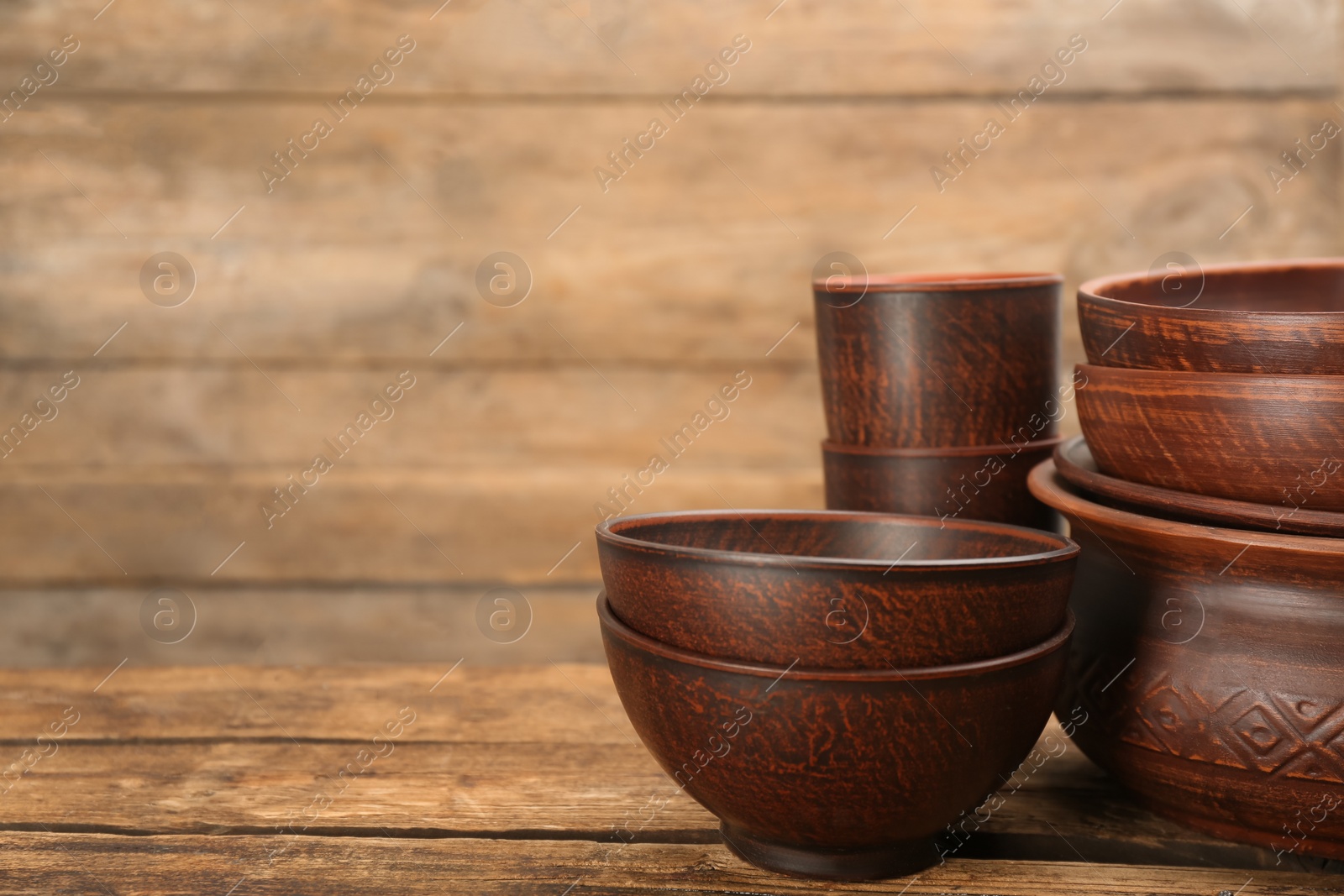 Photo of Set of clay utensils on wooden table. Space for text