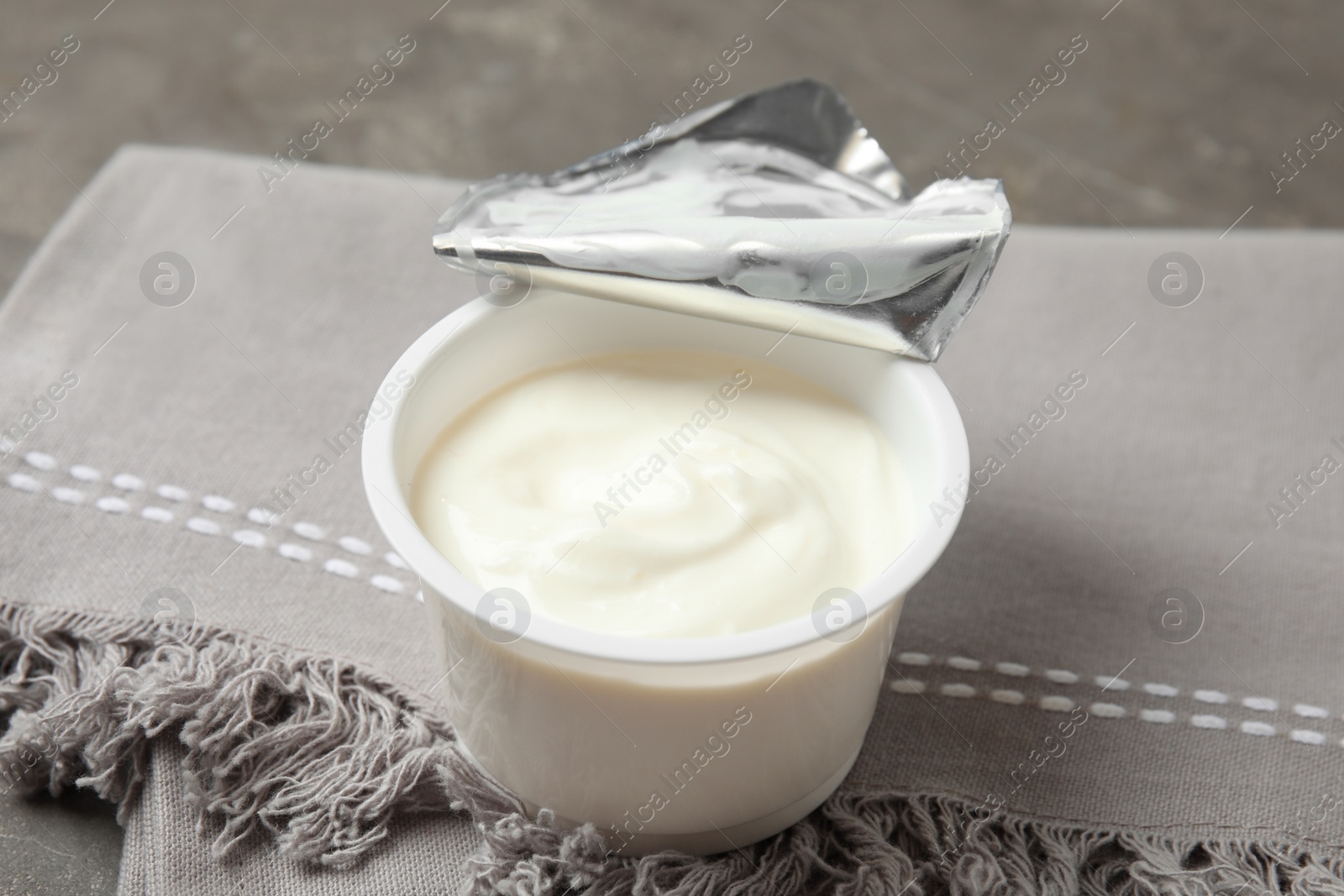 Photo of Plastic cup of fresh yogurt and napkin on table