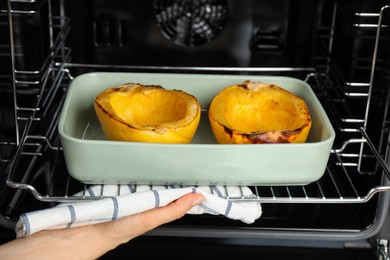 Photo of Woman taking baked spaghetti squash out of oven, closeup