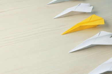 Photo of Handmade colorful paper planes on beige wooden table, space for text. Uniqueness concept